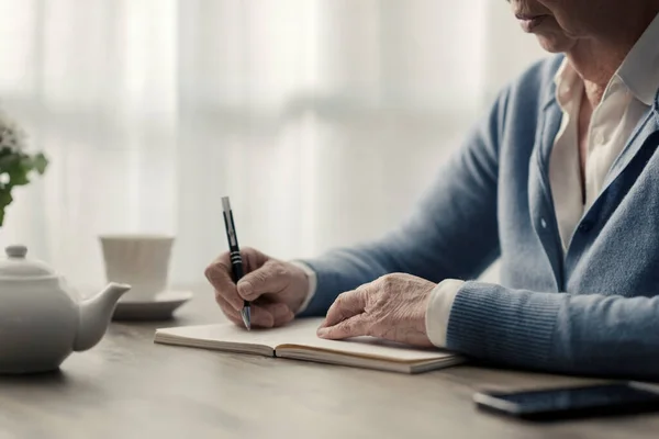 Mujer Mayor Sentada Escritorio Anotando Notas Cuaderno — Foto de Stock