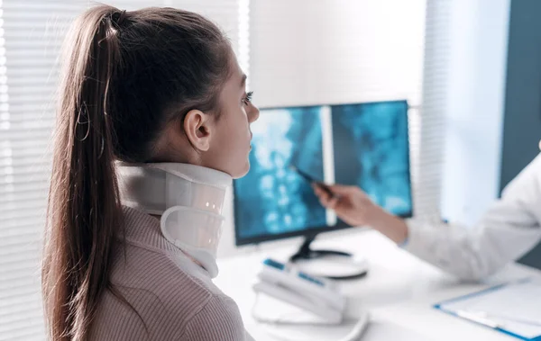 医生给病人解释了X光片 并指了指电脑屏幕 这名妇女戴着颈圈 — 图库照片