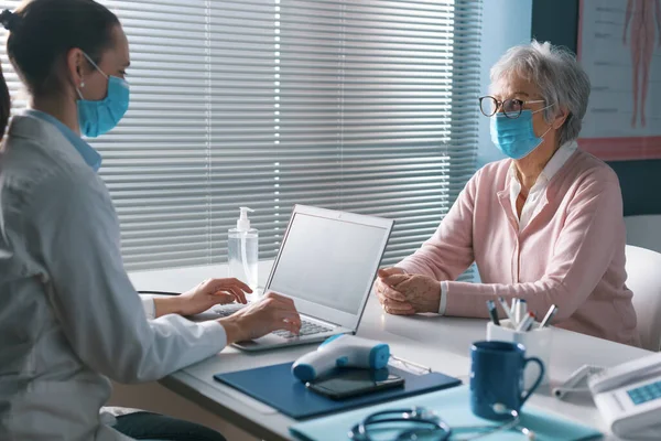 Doctor Reuniéndose Con Paciente Mayor Con Mascarilla Facial Comprobando Registros — Foto de Stock