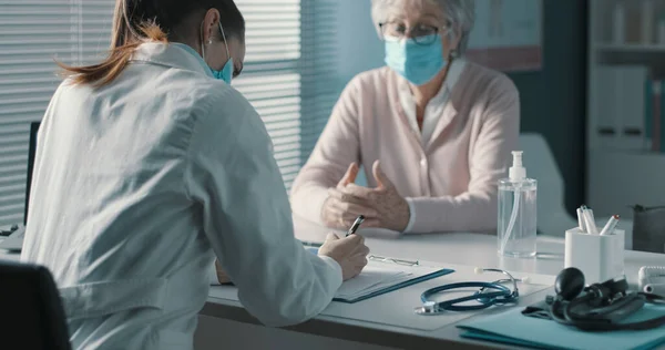 Médico Profesional Sentado Escritorio Escribiendo Una Receta Para Paciente Mayor — Foto de Stock