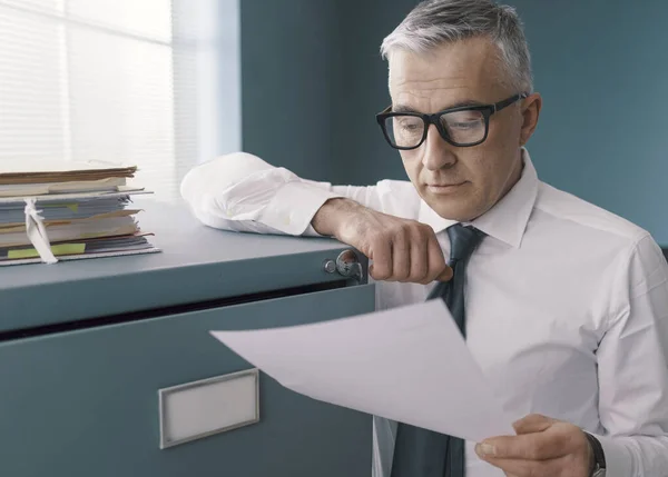 Zakelijke Zakenman Leunend Een Archiefkast Het Controleren Van Papierwerk — Stockfoto