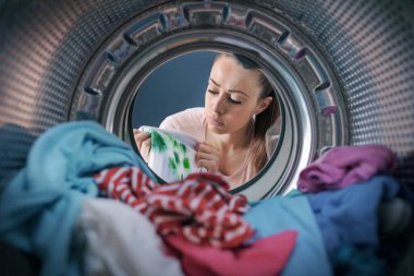 Disappointed woman finds stained clothes in the washing machine after doing laundry, point of view shot clipart