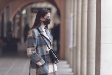 Yüz maskesi takan ve sokakta yürüyen genç bir kadın, yeni normal yaşam tarzı ve koronavirüs önleme konsepti