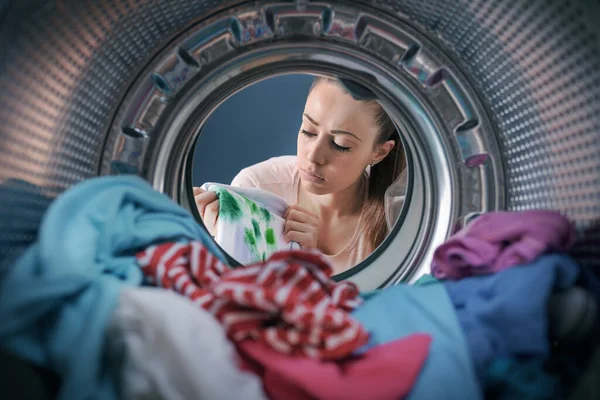 Disappointed woman finds stained clothes in the washing machine after doing laundry, point of view shot