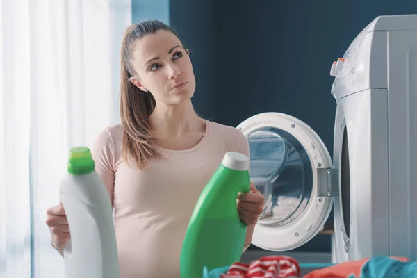 洗濯洗剤を比較して自宅で洗濯をする女性 — ストック写真