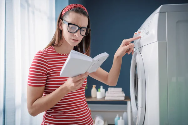 洗濯機の使い方や問題の解決方法を学ぶ女性は マニュアルの説明書をチェックしています — ストック写真