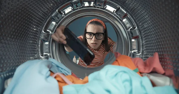 여자가 빨래를 세탁기에서 스마트폰을 — 스톡 사진