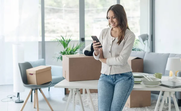 快乐的女人在新房子里用智能手机连接 她正在给她的朋友们打电话 — 图库照片