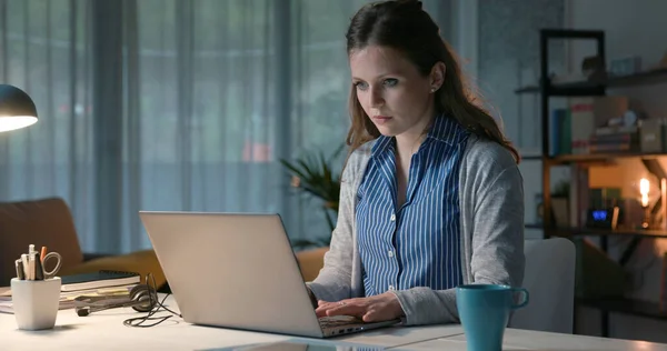 年轻妇女坐在办公桌前 在家工作 她在笔记本电脑上打字 — 图库照片
