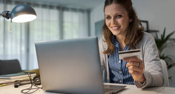 Masada Oturmuş Gülümseyen Genç Bir Kadın Internetten Kredi Kartı Kullanıyor — Stok fotoğraf