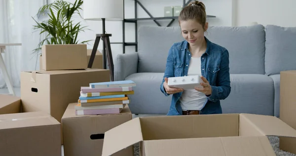 新しい家に引っ越してきた若い女性は 箱から物を取り出し 家の移転コンセプトを考えています — ストック写真