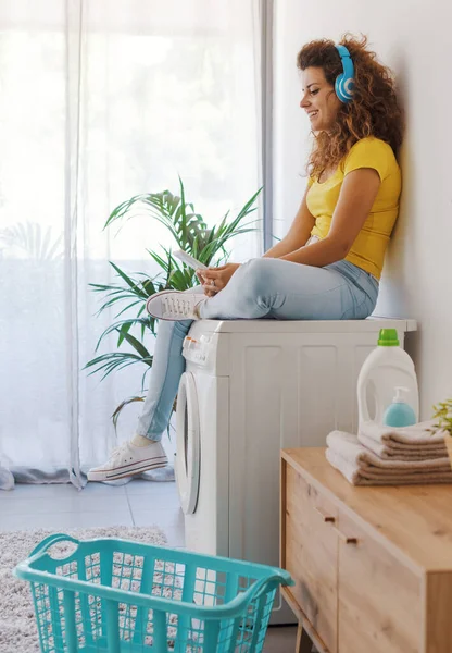 Çamaşır Makinesinde Oturup Çamaşırların Bitmesini Bekleyen Mutlu Genç Kadın Tabletine — Stok fotoğraf