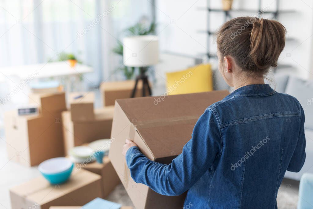 Woman carrying boxes in her new apartment, home relocation concept