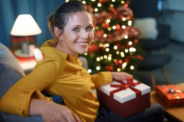 Mulher Feliz Sentada Sofá Segurando Presente Natal Ela Está Sorrindo — Fotografia de Stock