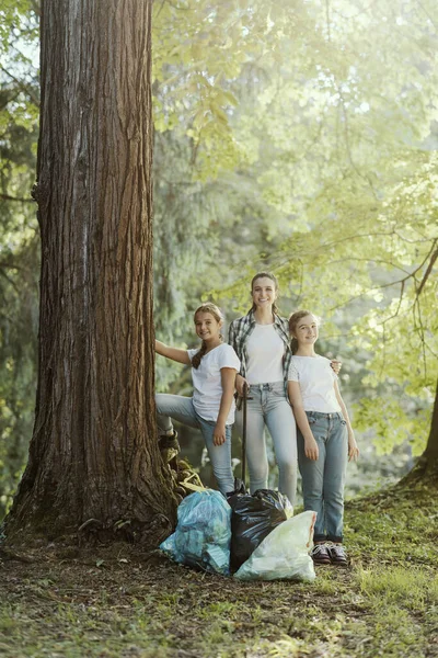 年轻的妇女清扫森林 收集垃圾 她们躺在一棵树旁 — 图库照片