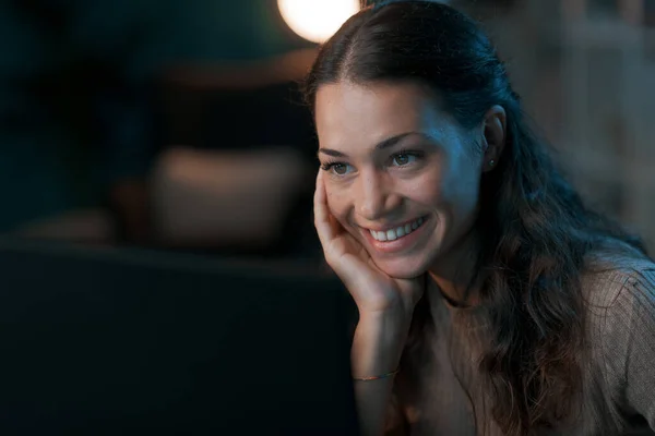 年轻的微笑的女人在晚上上网 她凝视着电脑屏幕 — 图库照片