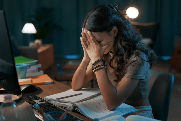 Depressed woman working and studying late at night, she is exhausted and sad