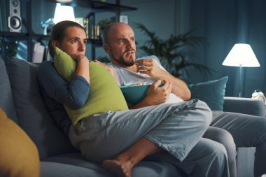 Kanepede oturup birlikte korku filmi izleyen bir çift.