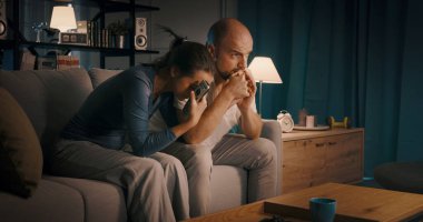 Çift kanepede oturuyor ve TV 'de bir drama filmi izliyor.