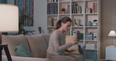 Kanepede oturan ve VR kulaklık takan genç bir kadın.