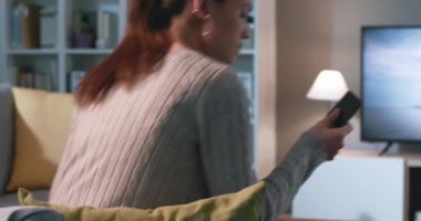 Kanepede oturan ve sanal gerçekliği yaşayan bir kadın.