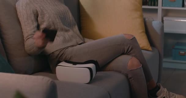 Mladá žena sedí na gauči a přistupuje k VR — Stock video