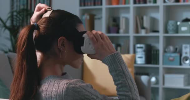 Mujer sentada en el sofá y experimentando la realidad virtual — Vídeos de Stock