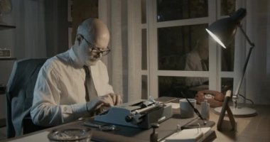 Profesör masada oturuyor ve bir telefon görüşmesi yapıyor.