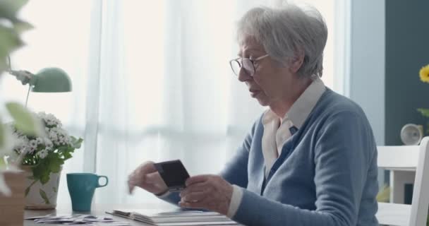 Старшая леди смотрит на свои старые фотографии — стоковое видео