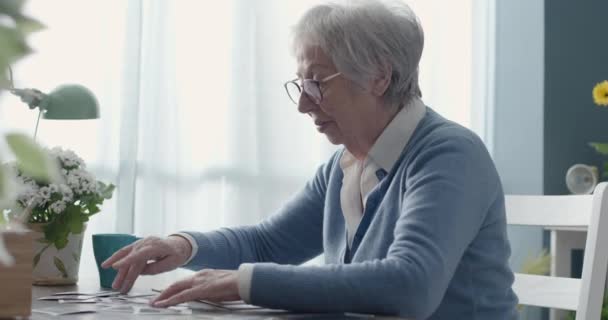 Senior kvinna tittar på gamla bilder — Stockvideo