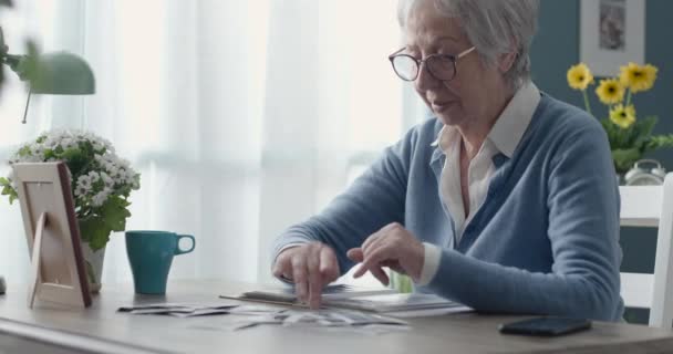 Senior vrouw op zoek naar oude foto 's — Stockvideo