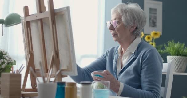 Kreatywny starszy kobieta malarstwo na płótnie — Wideo stockowe