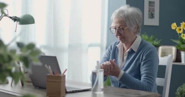 Oudere vrouw die ontsmettingsmiddel op haar handen aanbrengt — Stockvideo