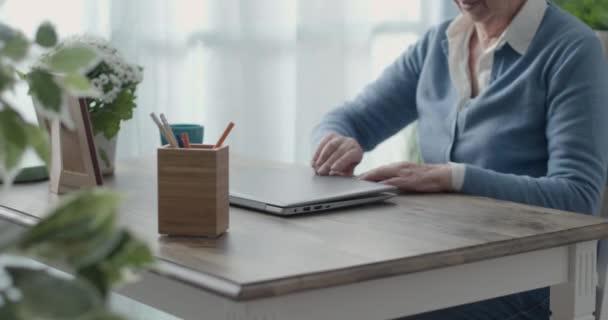 Старша жінка використовує ноутбук вдома — стокове відео
