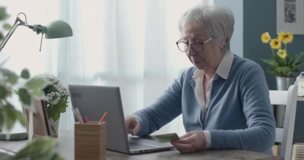 Старша жінка використовує кредитну картку онлайн — стокове відео