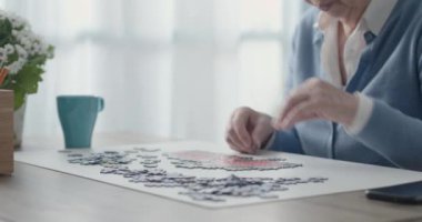 Evde bulmaca çözen yaşlı bir kadın.