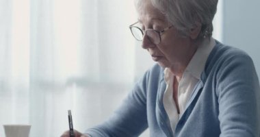 Not defterine yazan yaşlı kadın.