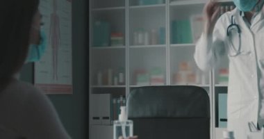 Bir hastayı ziyaret etmeden önce cerrahi maske takan bir doktor