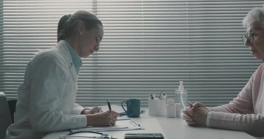 Doktor kıdemli bir hasta için reçete yazıyor.