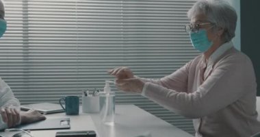 Kıdemli kadın doktorun ofisinde ellerini dezenfekte ediyor.