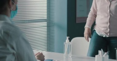 Doktorun ofisinde kıdemli hasta ellerini dezenfekte ediyor.