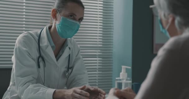 Médico e paciente sênior conversando juntos no escritório — Vídeo de Stock