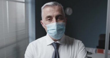 Cerrahi maske takan bir iş adamı.