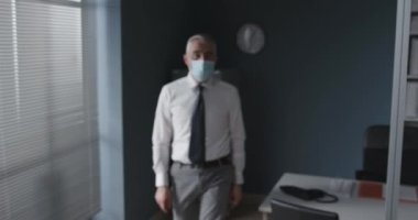 Cerrahi maske takan bir iş adamı.