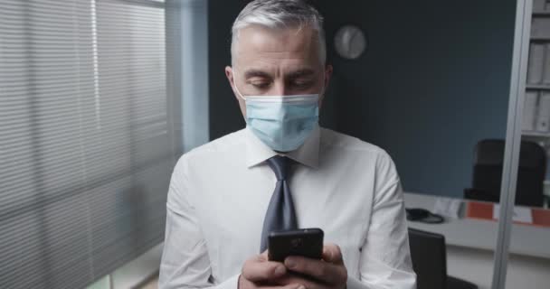 Бизнесмен в маске с помощью смартфона — стоковое видео