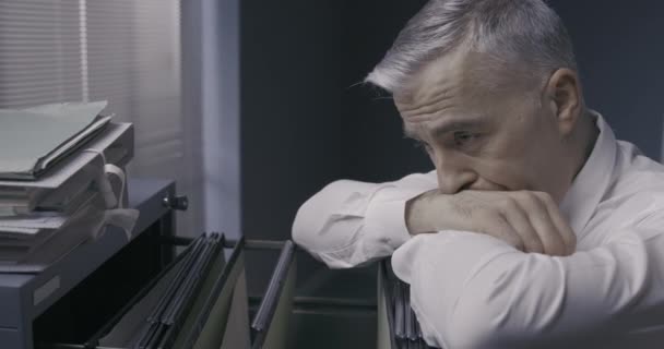 Депрессивный бизнесмен, опирающийся на шкаф для бумаг — стоковое видео