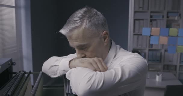 Депрессивный бизнесмен, опирающийся на шкаф для бумаг — стоковое видео