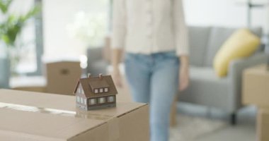 Elinde model bir ev tutan ve gülümseyen bir kadın