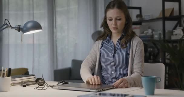 Kobieta siedzi przy biurku i zaczyna pracować. — Wideo stockowe