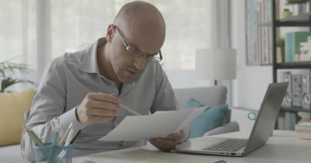 Skuffende forretningsmand, der kontrollerer papirarbejde – Stock-video